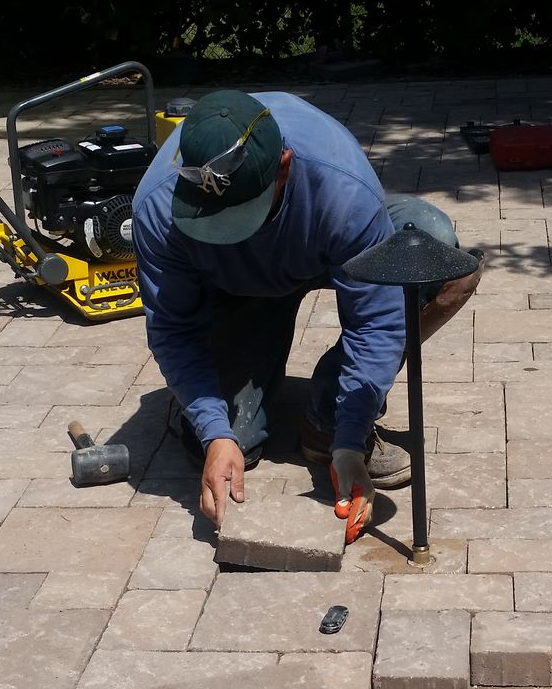 Homeowner replacing a paver on a Colorado residential backyard walkway — surface-level repairs are manageable DIY weekend projects for handy homeowners