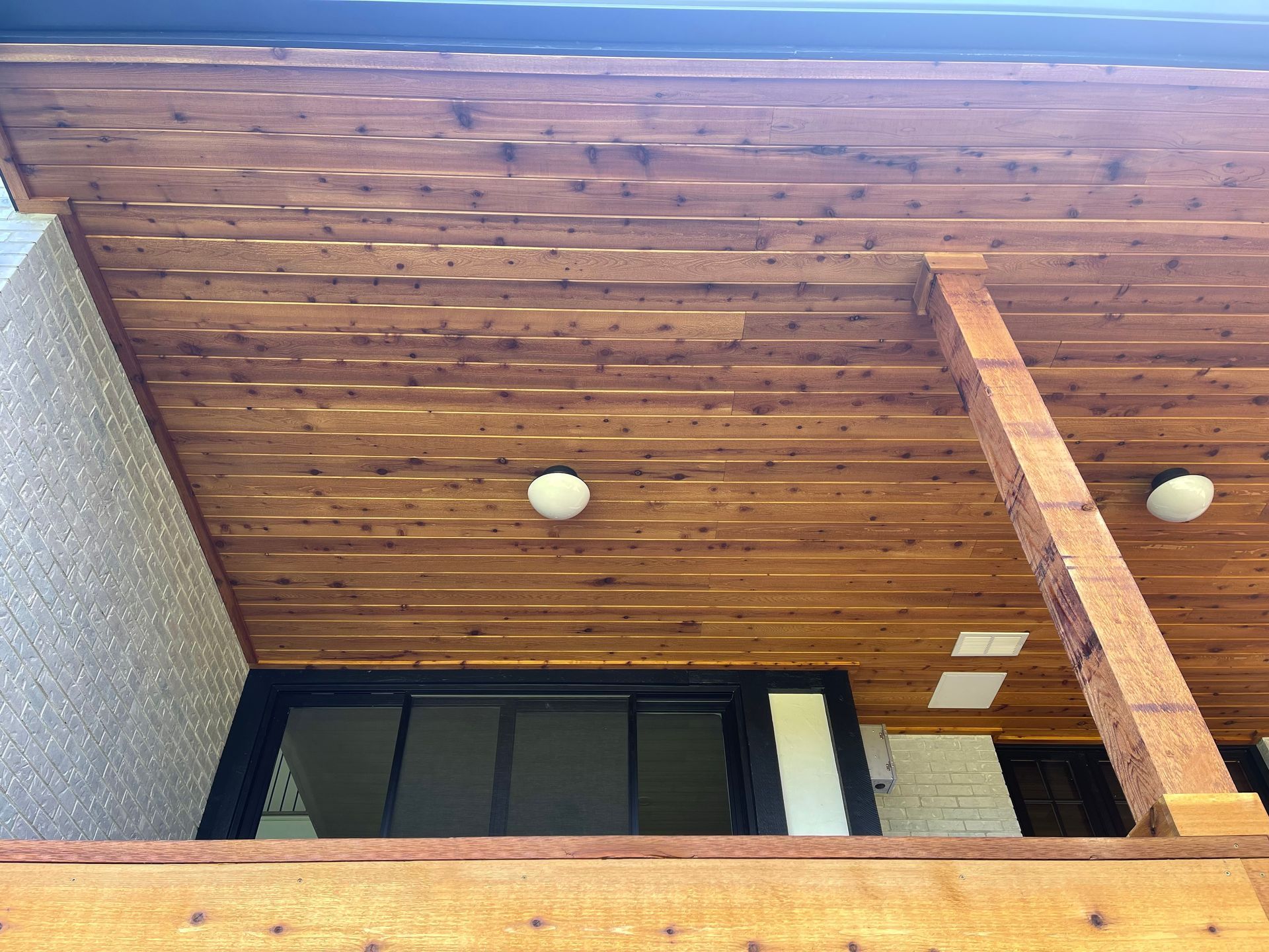 The ceiling of a house with wood paneling and a sliding glass door.