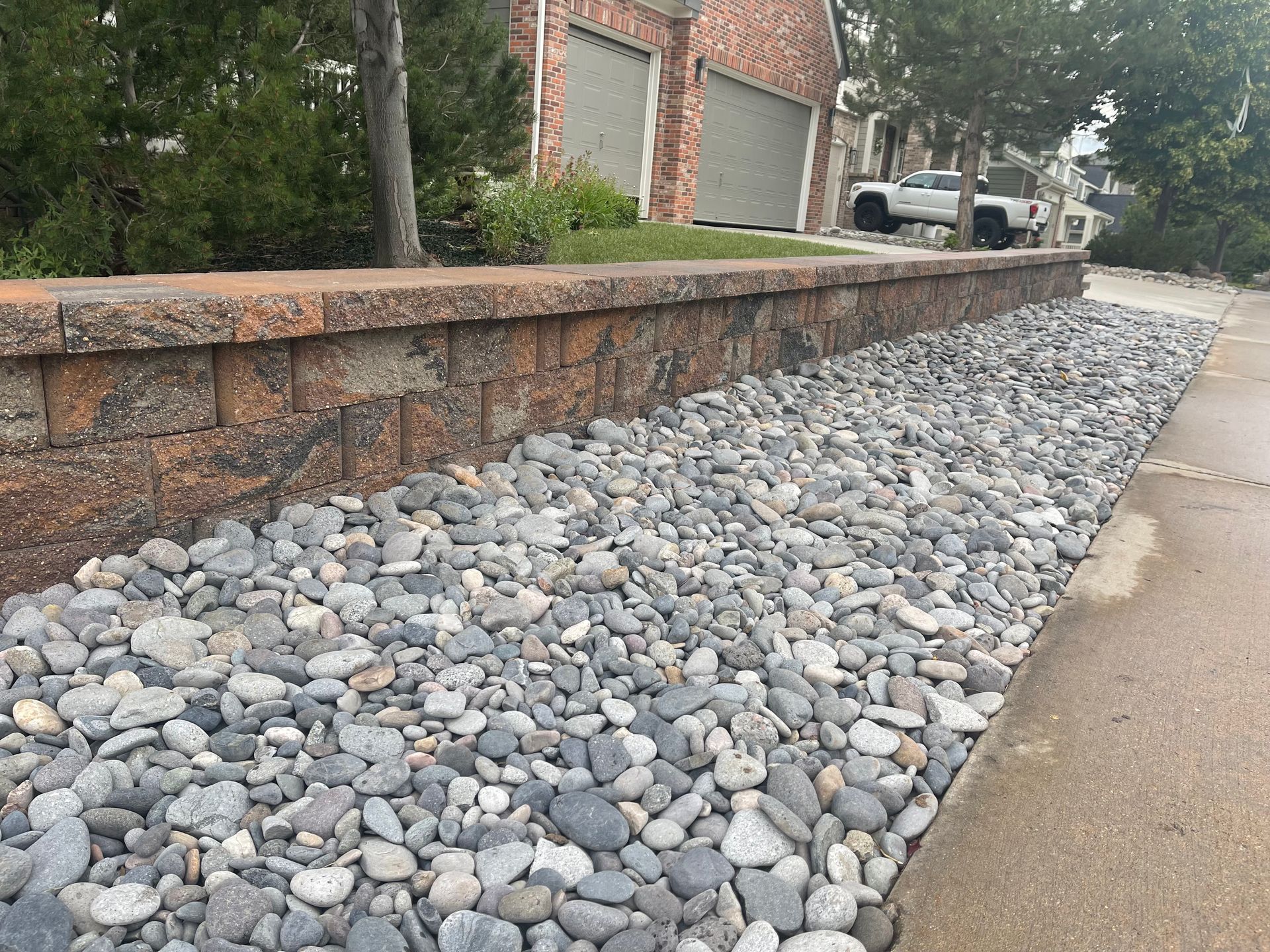 A pile of rocks is sitting on the sidewalk next to a brick wall.