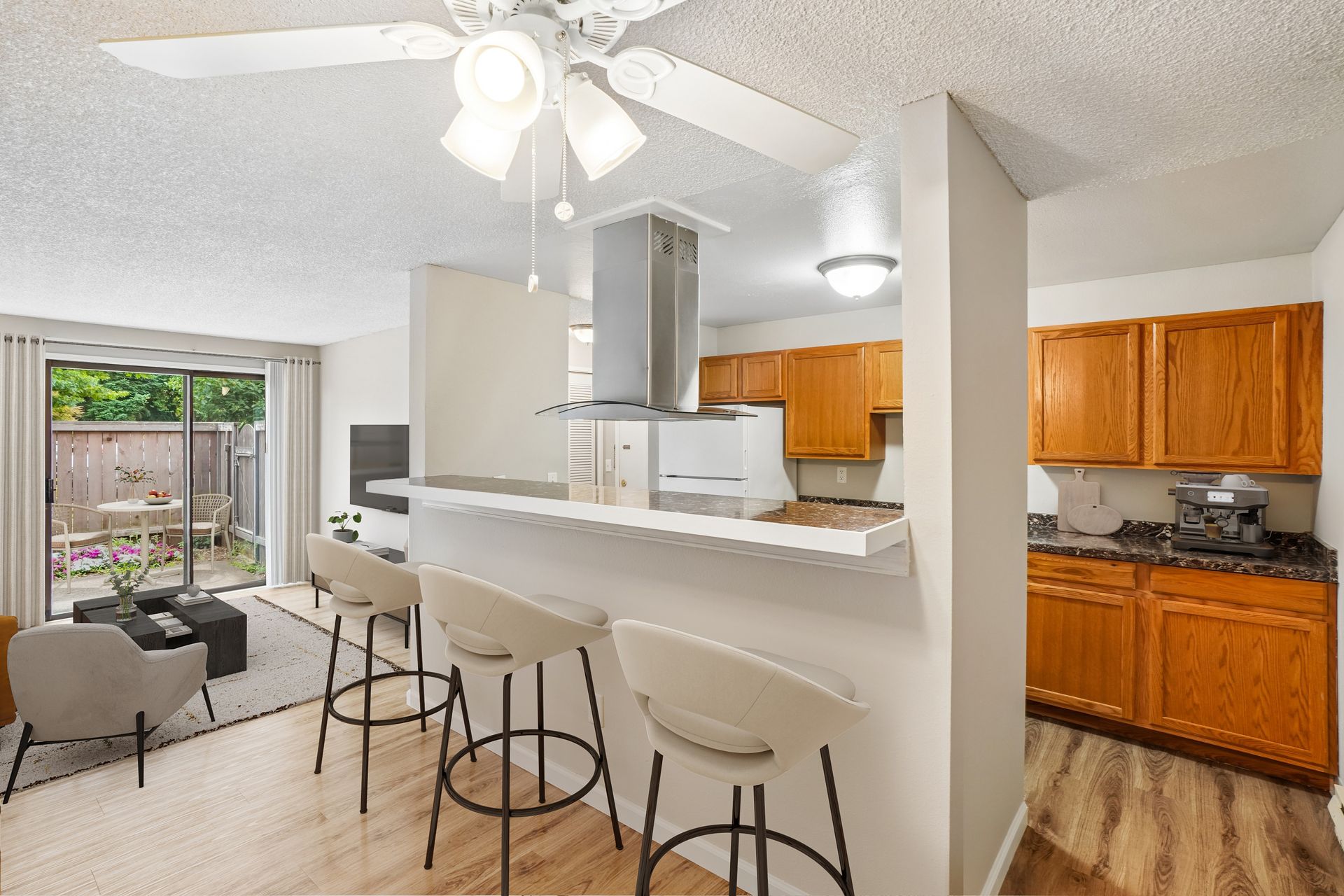 Bright open kitchen and dining area with breakfast bar, stools, and sliding glass door to patio.