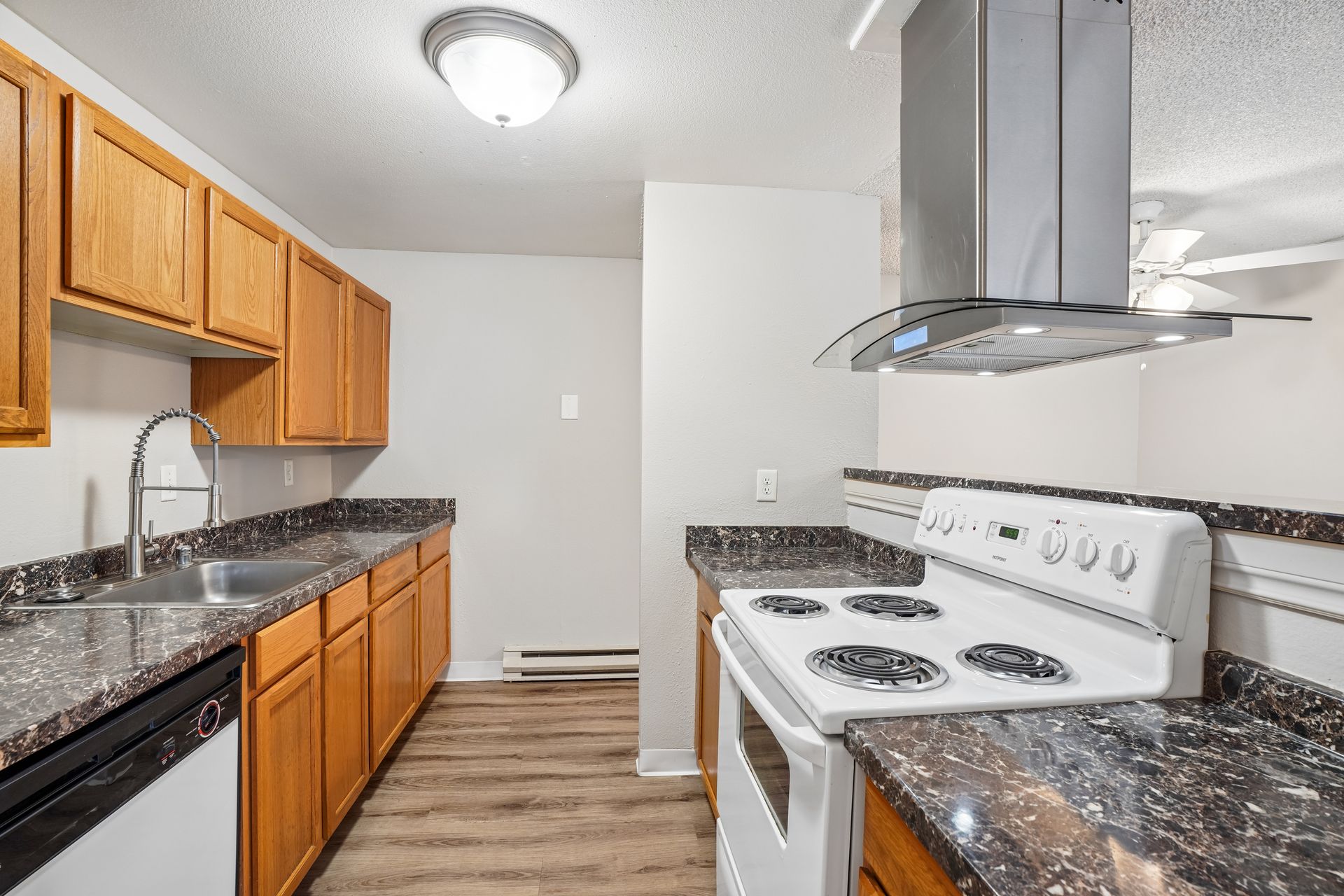 Kitchen with white appliances, wood cabinets, and granite-style countertops