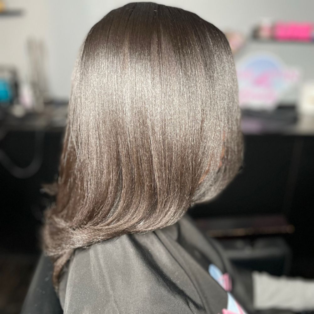 Side view of a sleek, layered brunette bob with soft highlights in a salon setting