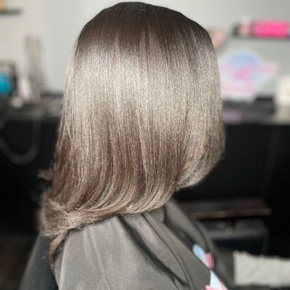 Side view of a sleek, layered brunette bob with soft highlights in a salon setting