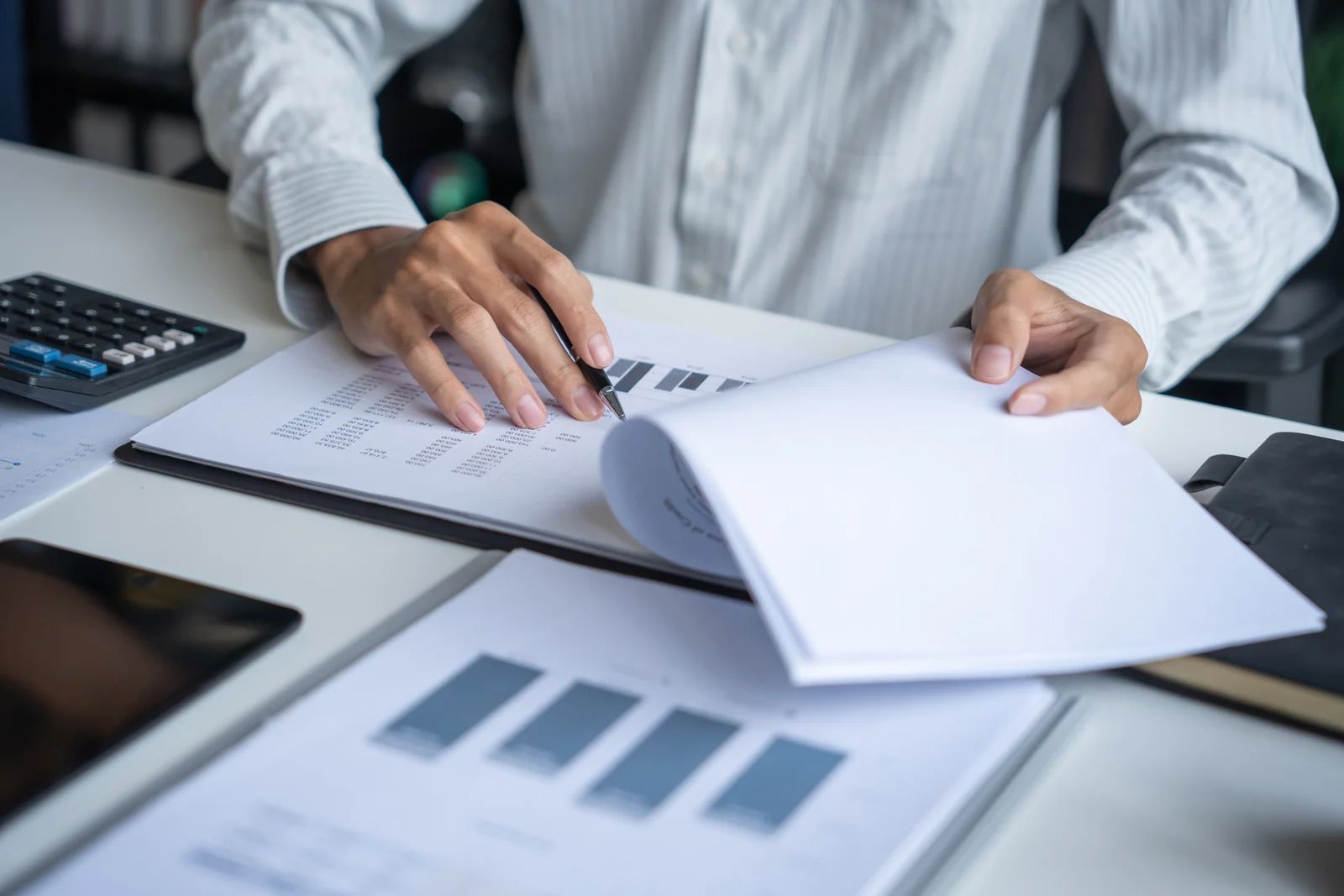 Person reviewing financial documents at a desk with charts and a calculator