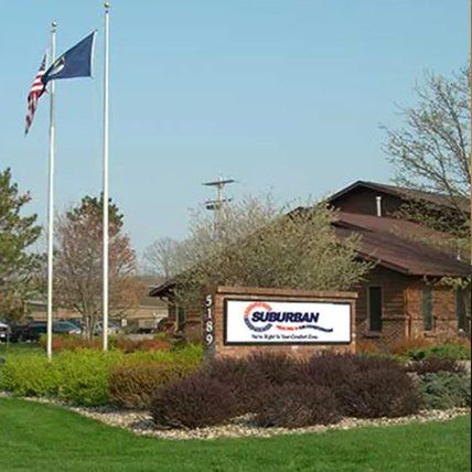Sign for Suburban with building and flags in front.