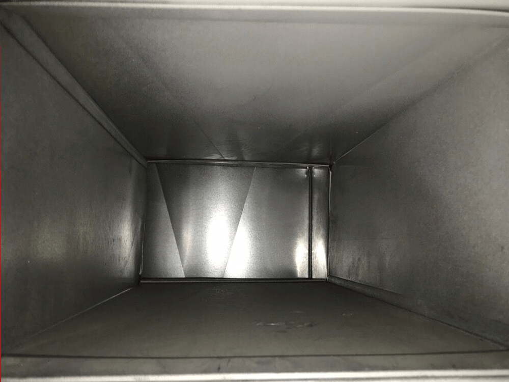 Inside view of a rectangular metal duct, with slightly shiny silver walls and a flat floor.