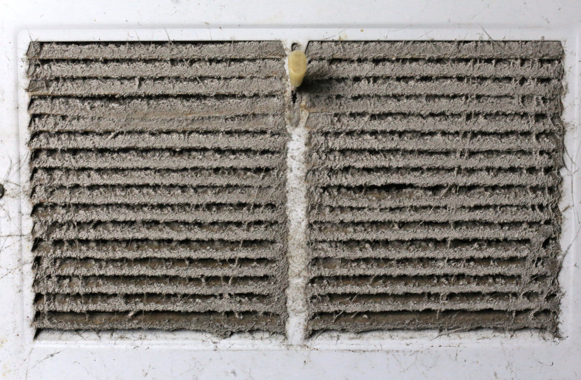 AC Installation — Kalamazoo, MI — Suburban Heating & Air Conditioning Dirty, dusty air vent; rectangular, white frame, filled with thick gray buildup.