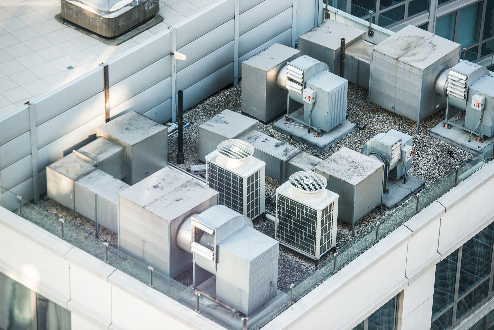 Rooftop with various HVAC units, including air conditioners, ducts, and vents, atop a modern building.