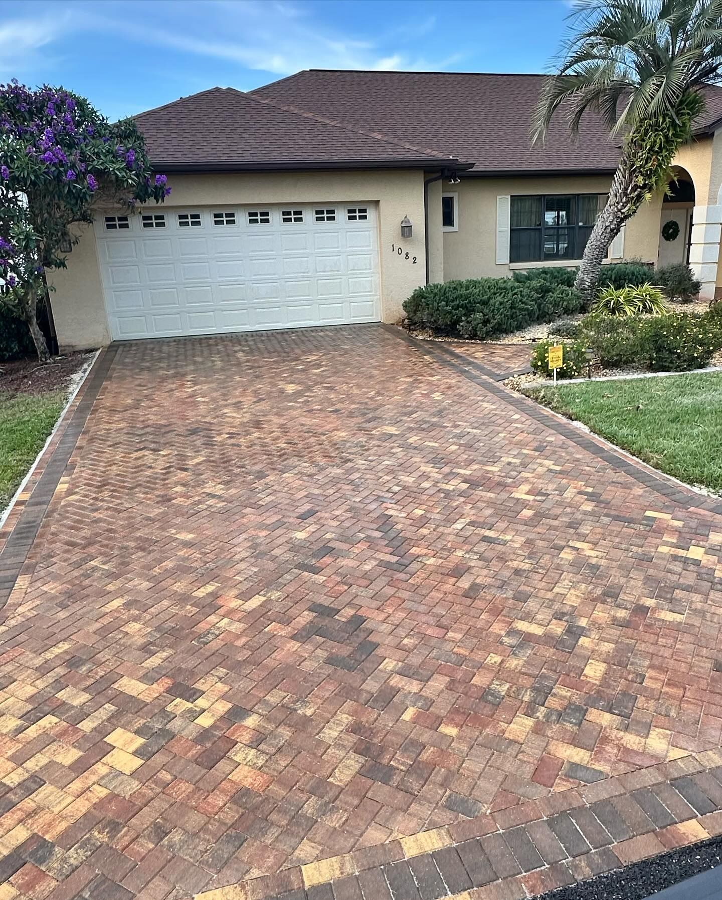 A brick driveway leading to a house with a white garage door.
