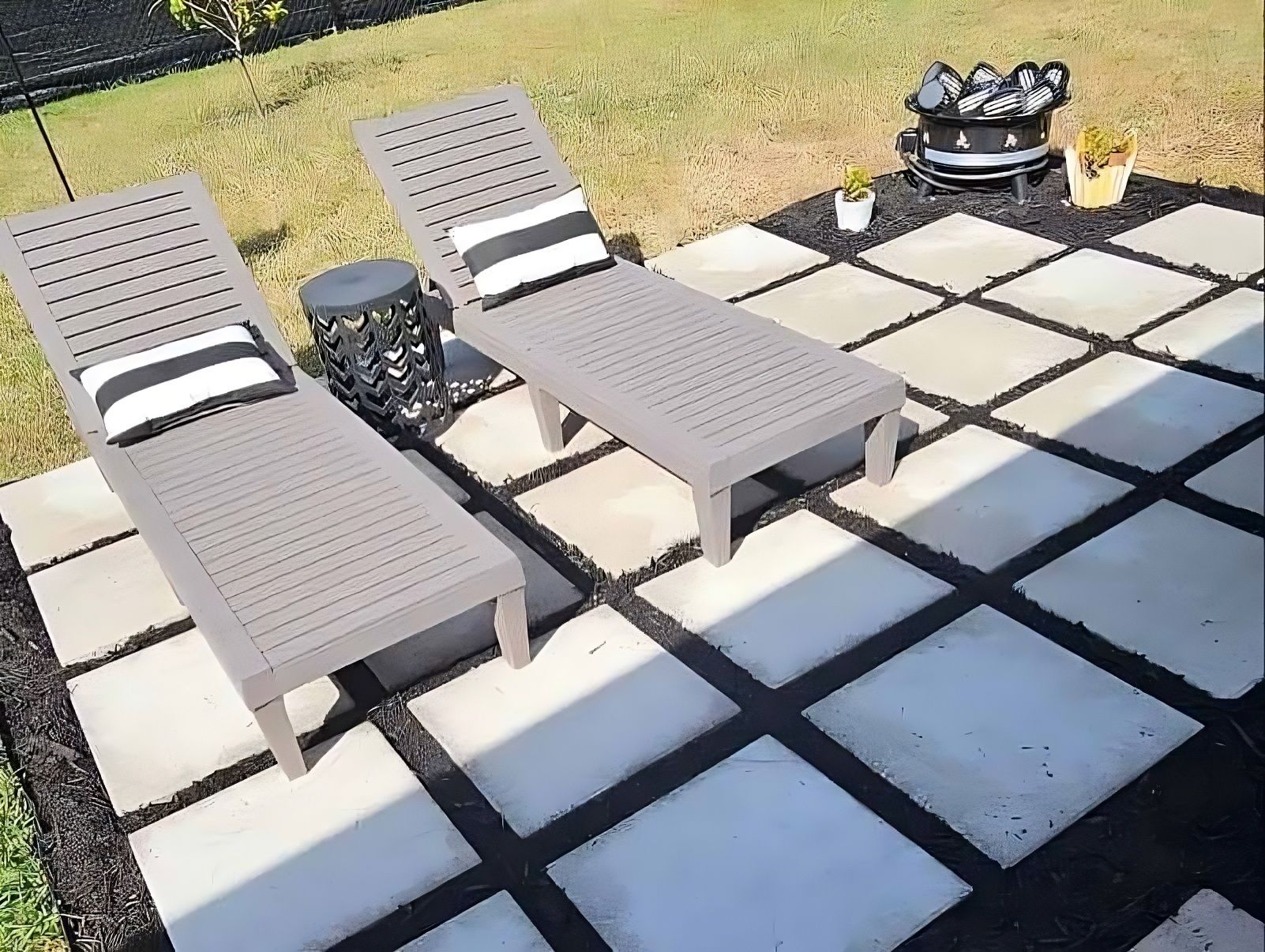 Two lounge chairs are sitting on a patio with a fire pit in the background.