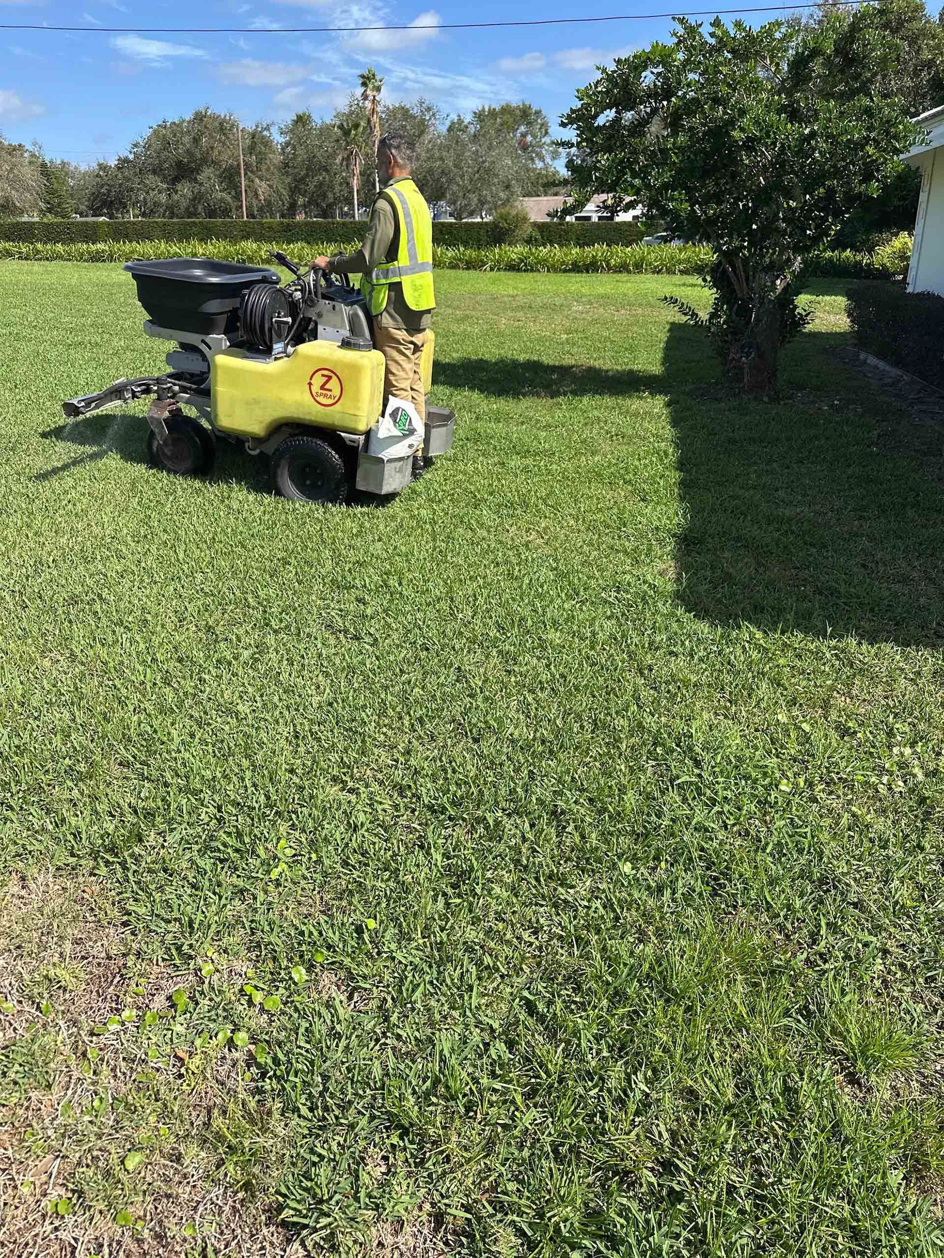 A man is riding a lawn mower through a lush green field.