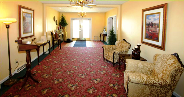 A long hallway with a red carpet and chairs