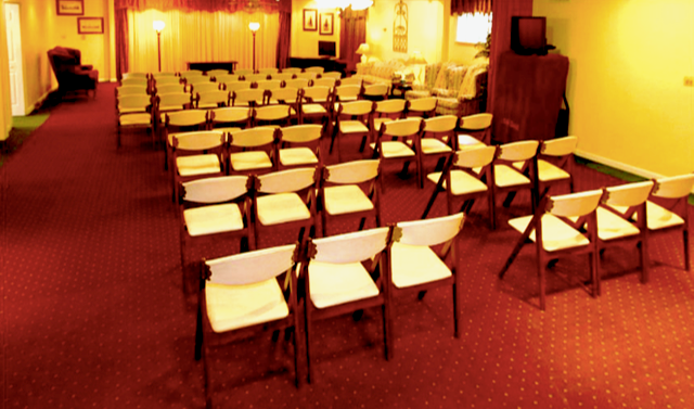 Rows of folding chairs in a room with a red carpet