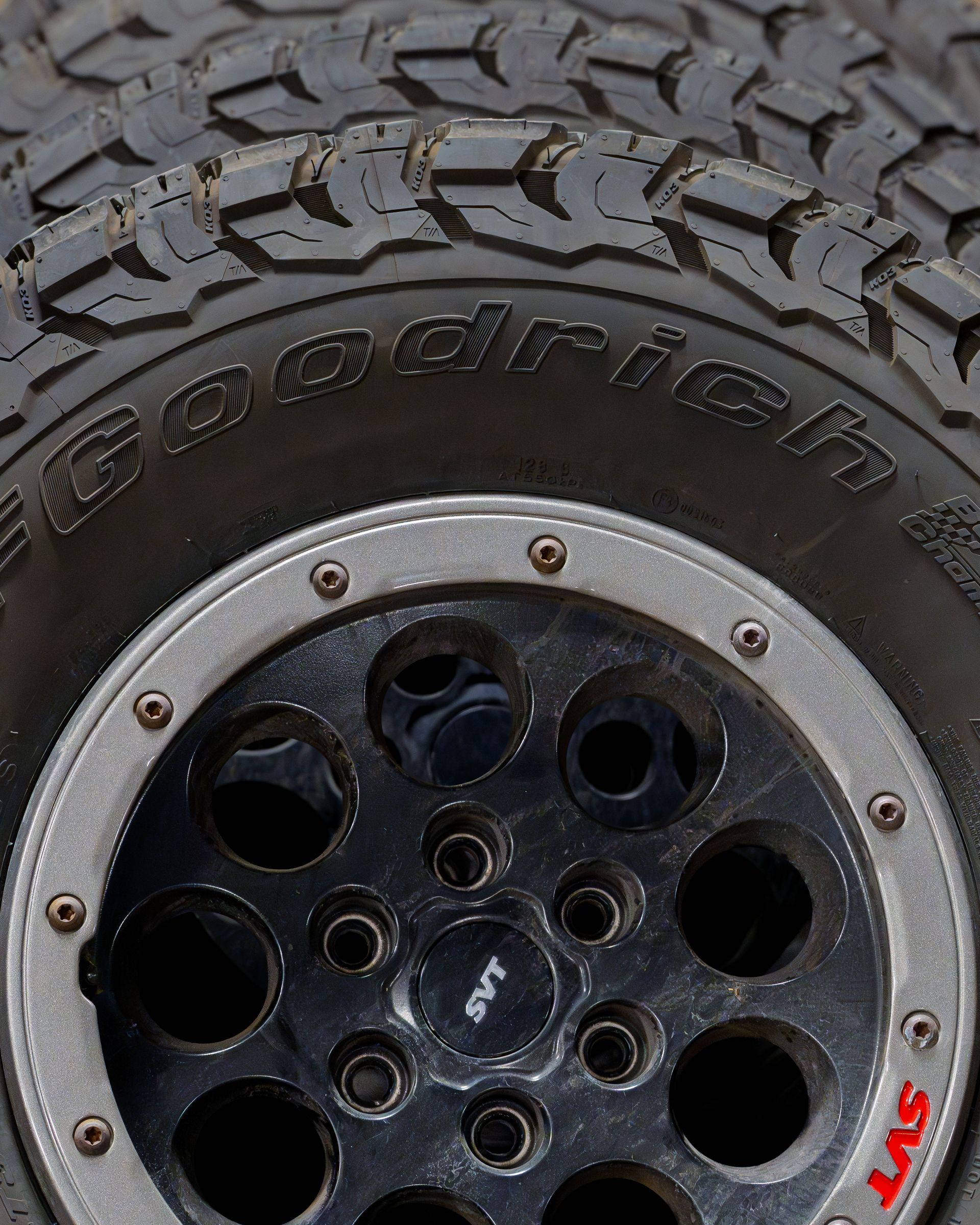 Close-up of a rugged off-road tire and black wheel rim with silver bolts