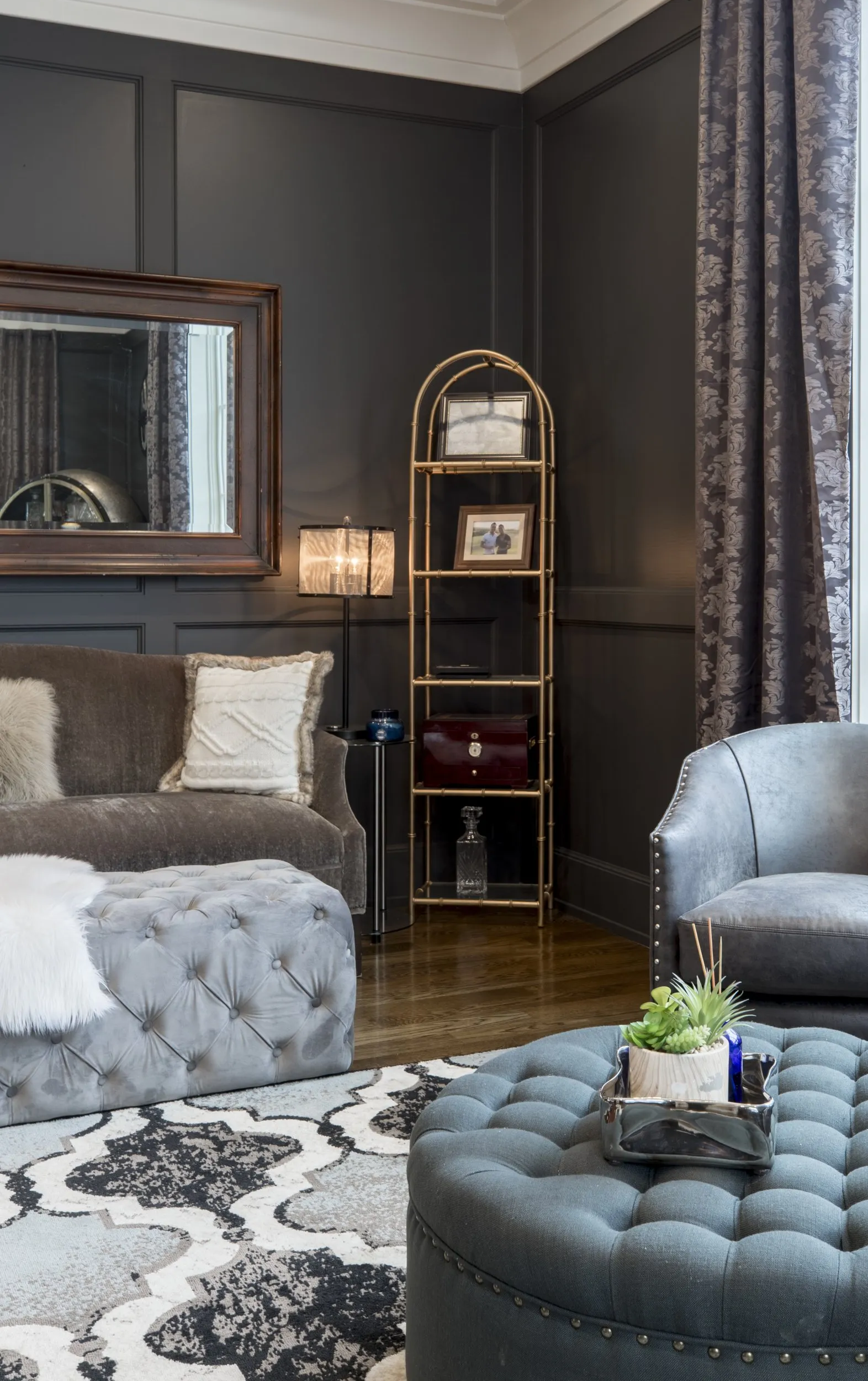 A living room with a couch , chairs , ottoman and a mirror