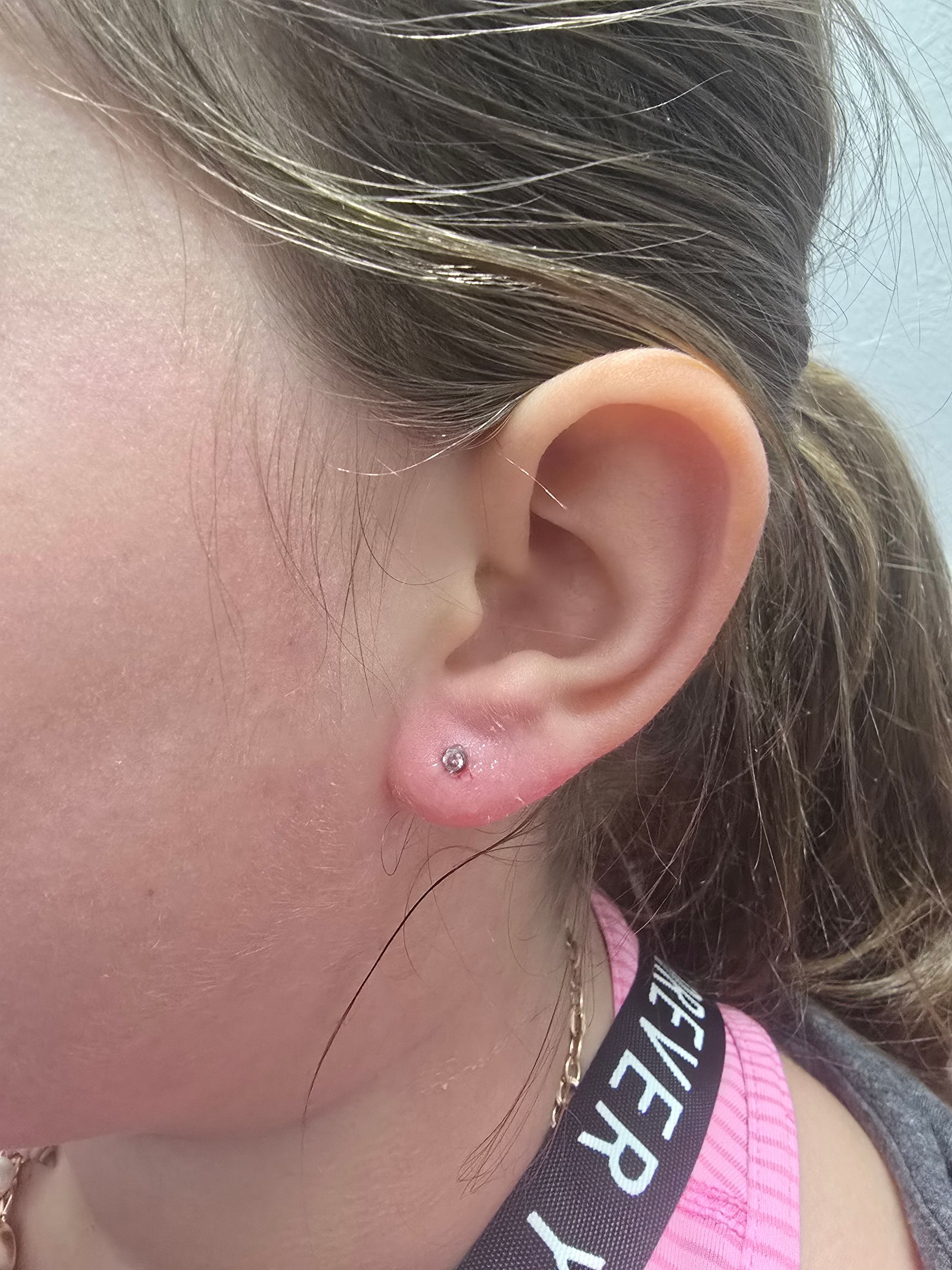 A close up of a young girl 's ear with earrings.