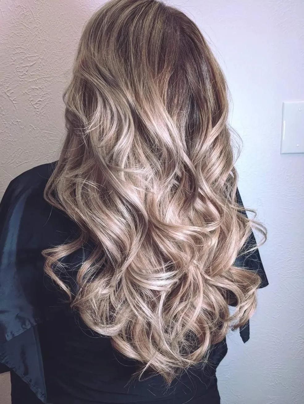 A woman with long wavy blonde hair is wearing a black robe.