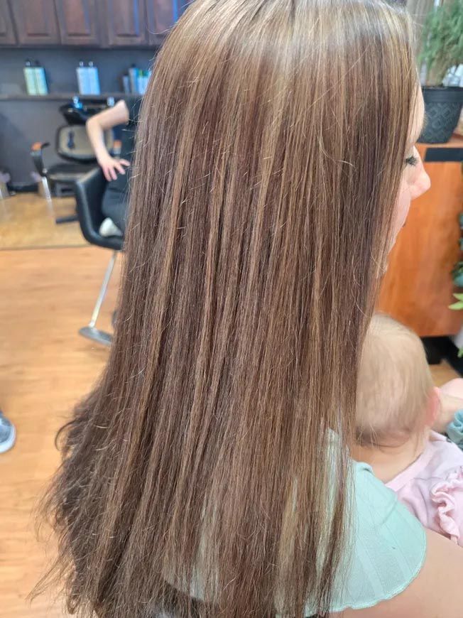 A woman with long hair is holding a baby in a salon.