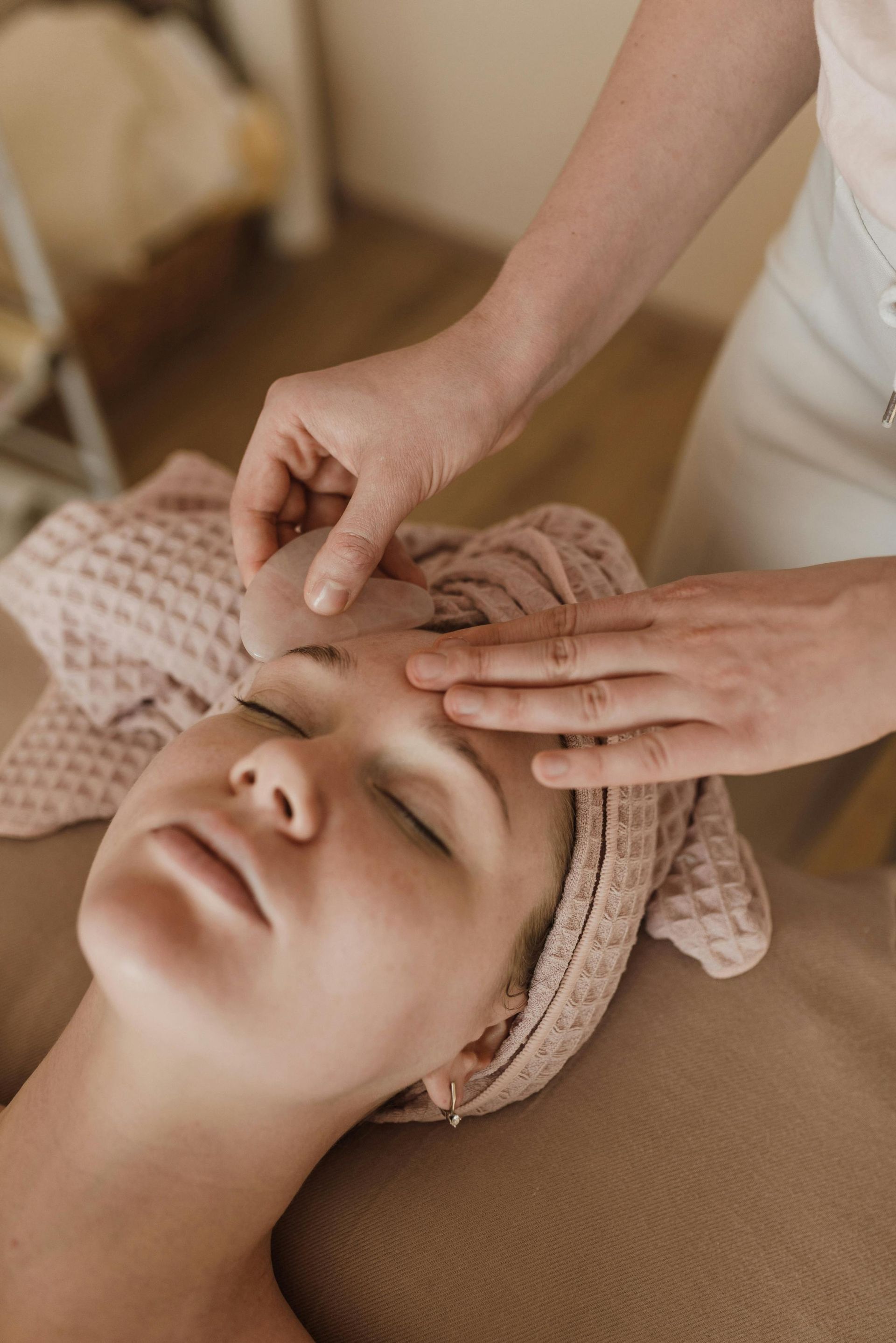 A woman with a towel wrapped around her head is getting a facial massage.
