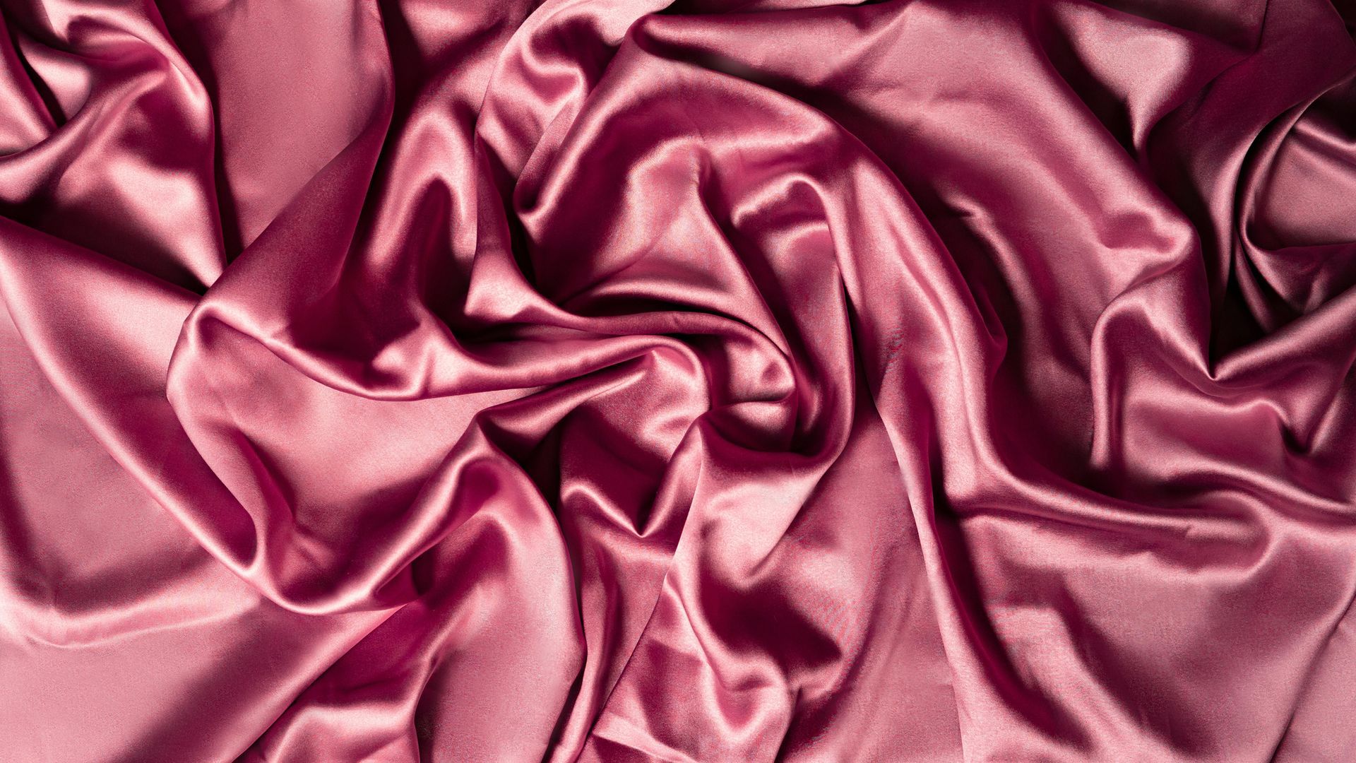 A close up of a pink satin fabric with waves