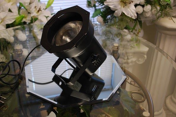 Black spotlight on a glass table beside a laptop and white flowers