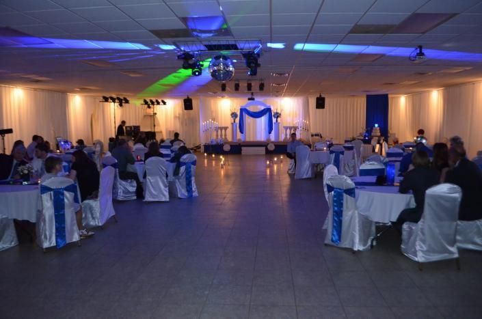 Banquet hall with blue-lit stage, decorated tables, and seated guests at a formal event