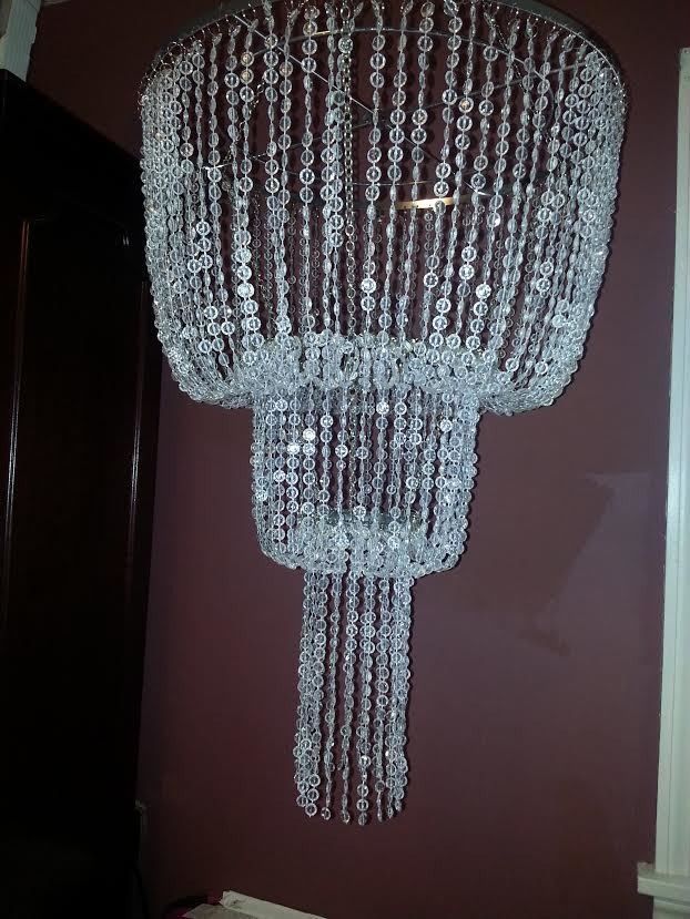 Crystal chandelier hanging in a dim hallway against maroon walls