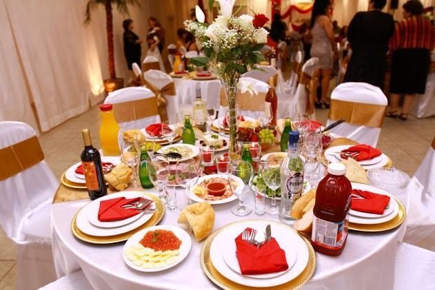 Decorated banquet table with red and white tableware, drinks, flowers, and desserts at a festive event
