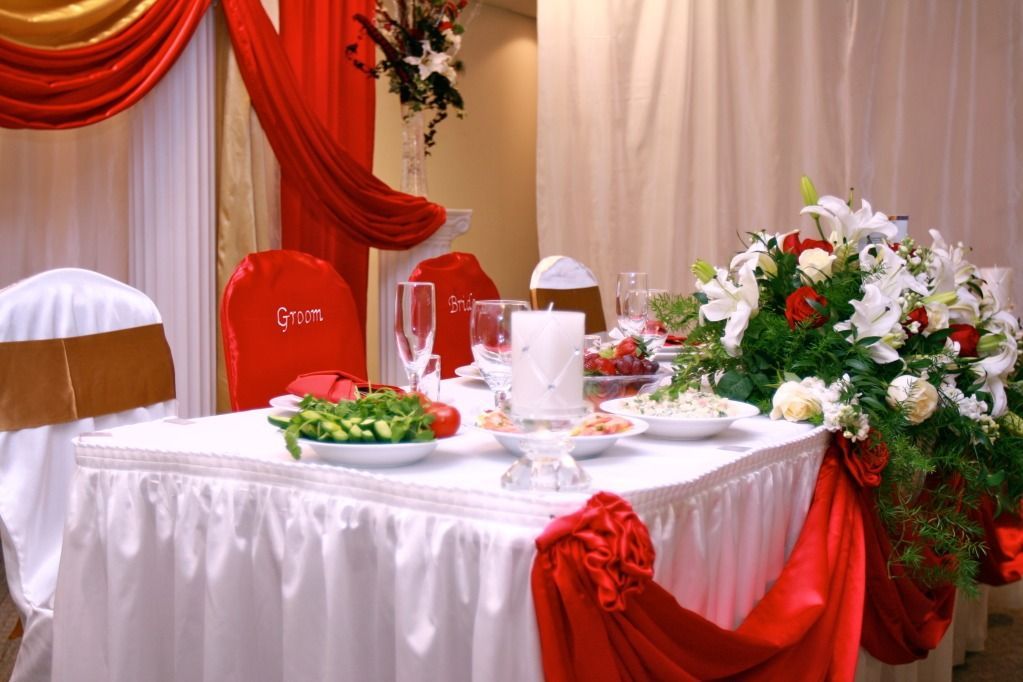 Elegant banquet table with white cloth, red drapery, floral centerpiece, and place settings