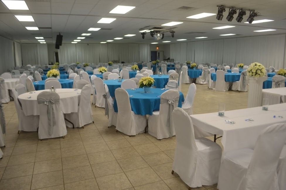 Banquet hall with round tables, white chair covers, blue tablecloths, and floral centerpieces