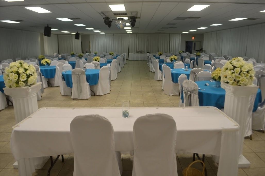 Decorated banquet hall with white and blue table settings and chairs arranged for an event