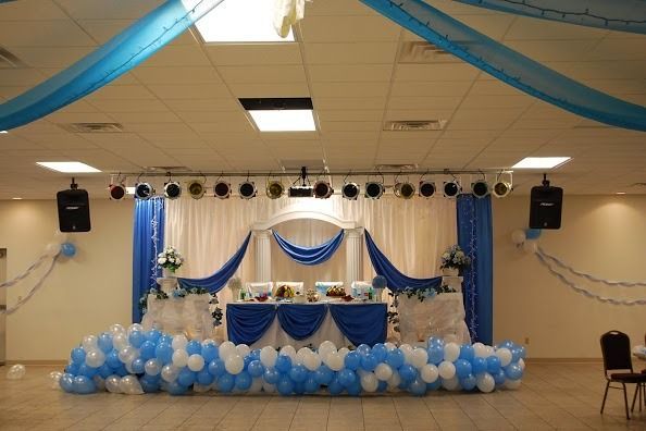 Blue-and-white decorated banquet stage with balloons, drapes, and a table at the center