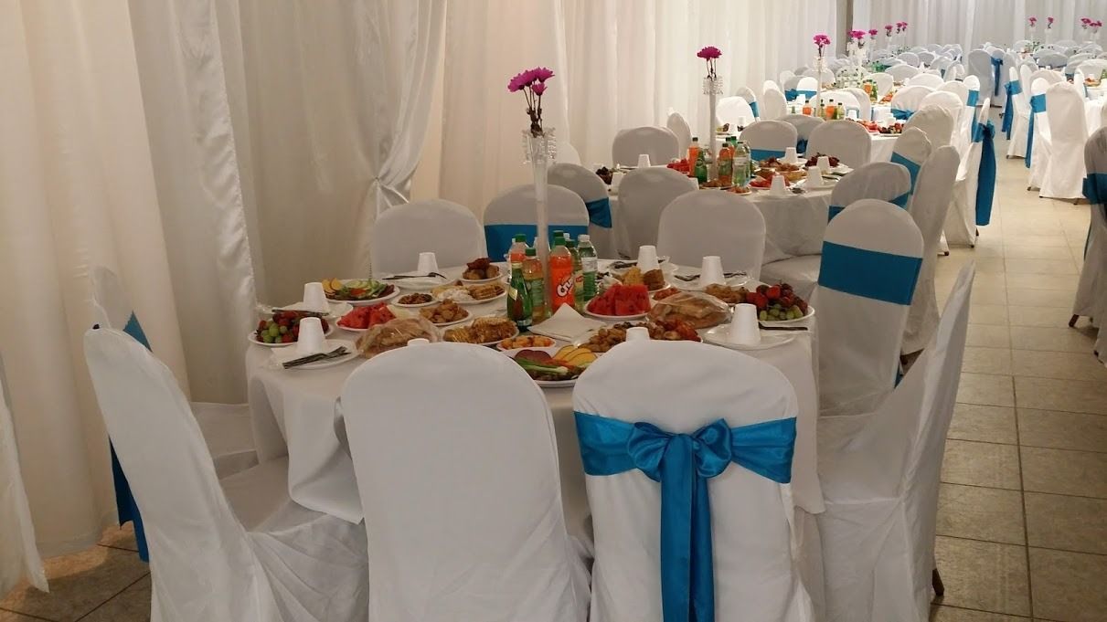 Decorated banquet tables with white chair covers and blue bows in a bright event hall