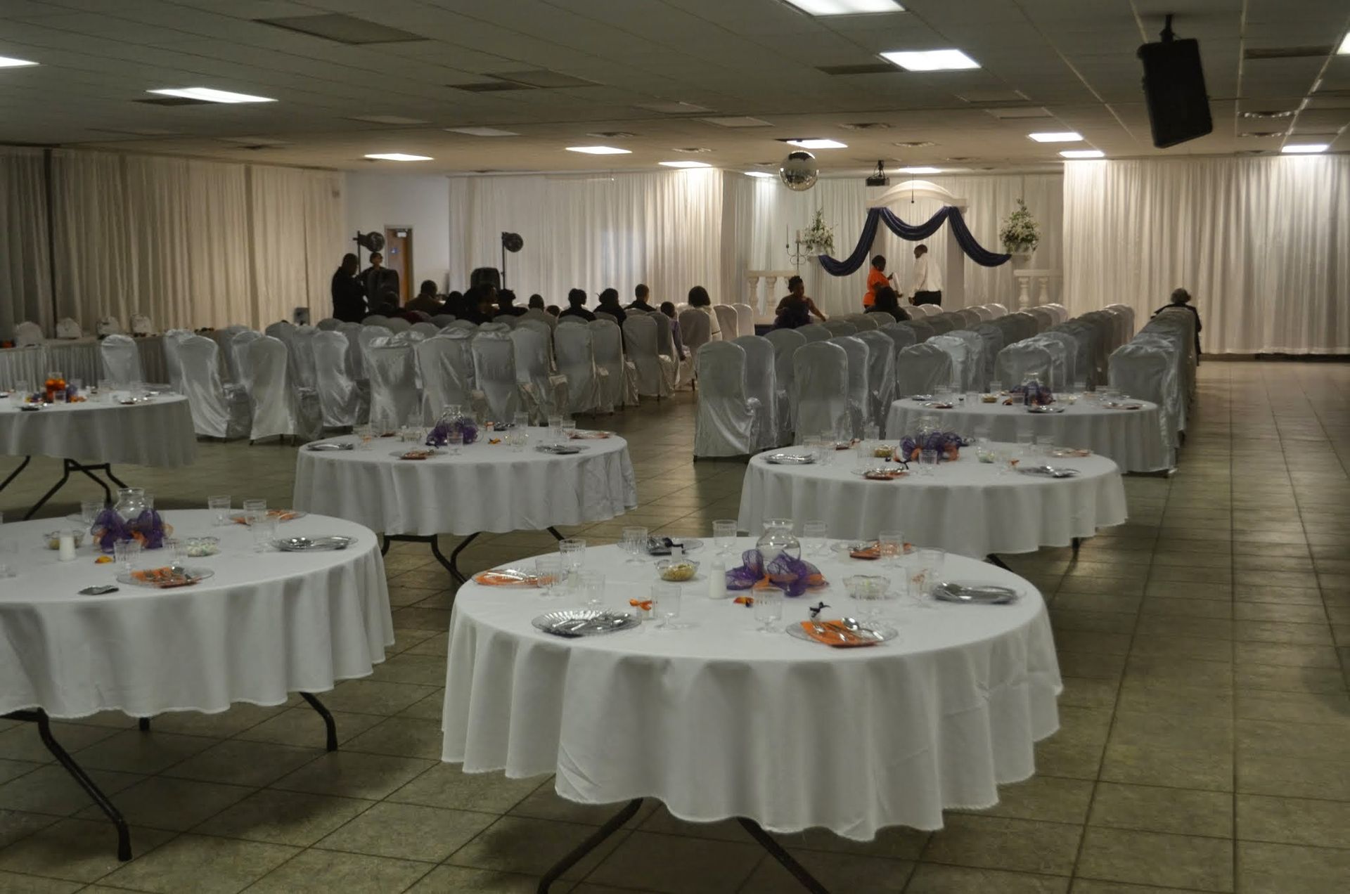 Banquet hall with round tables draped in white and a decorated head table at the front