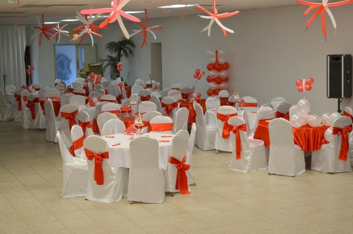 Decorated banquet hall with white chair covers, red sashes, and hanging red star decorations