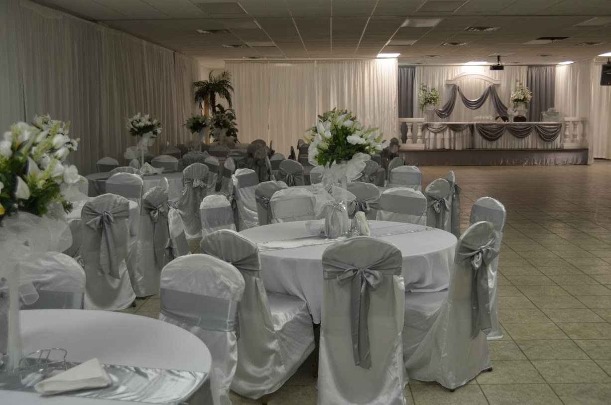 Banquet hall with round tables and white chair covers decorated with gray bows, set for an event