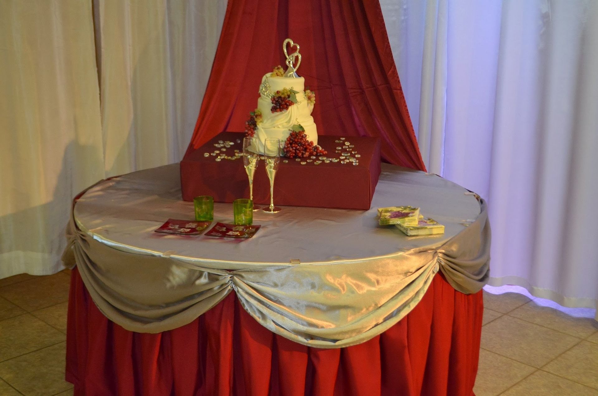 Red and silver decorated table with floral centerpiece and gift boxes under draped curtains