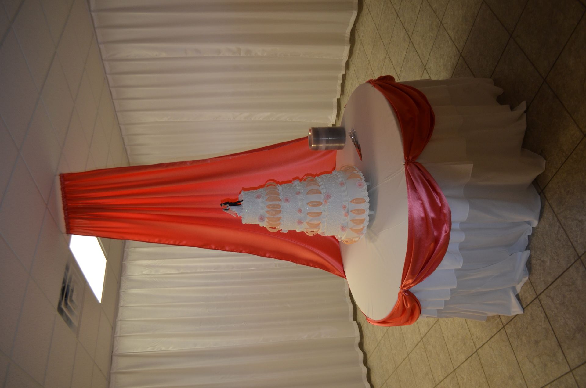 Red-and-white draped event table with a tiered display in front of cream curtains