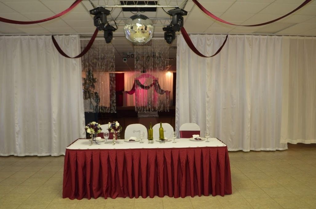 Decorated banquet table with white chairs and red drapes in a formal event hall