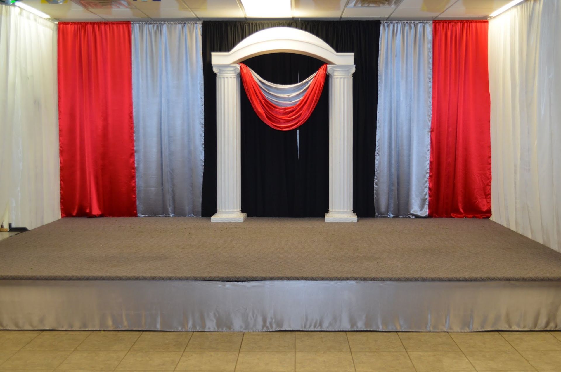 Empty stage with white columns and red, silver, and black drapes