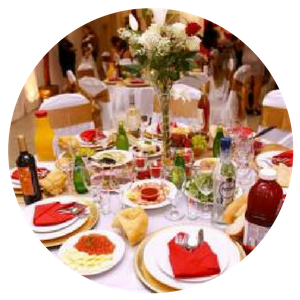 Round banquet table set with red napkins, plates, bottles, and flower centerpiece at a formal event