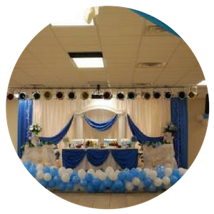 Blue-and-white decorated banquet stage with draped backdrop and balloon border
