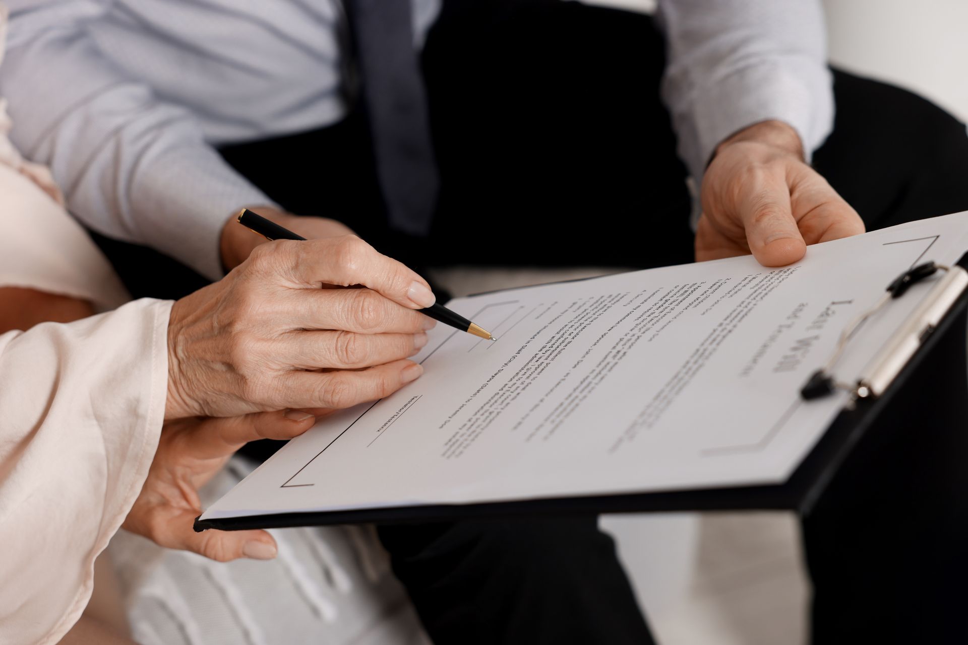 Real estate meeting with a house model, documents, calculator, and hands discussing a contract on a table