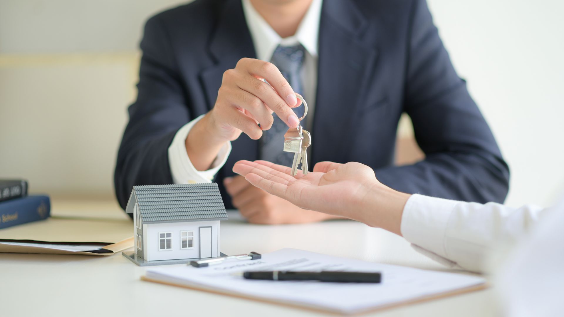 Businessperson handing over house keys across a desk in a real estate office