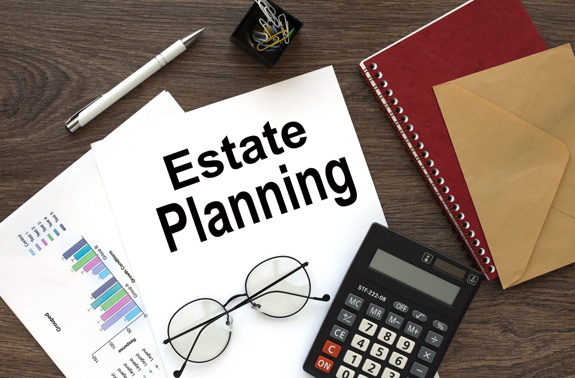 Estate planning documents on a desk with glasses, calculator, pen, notebook, and envelopes
