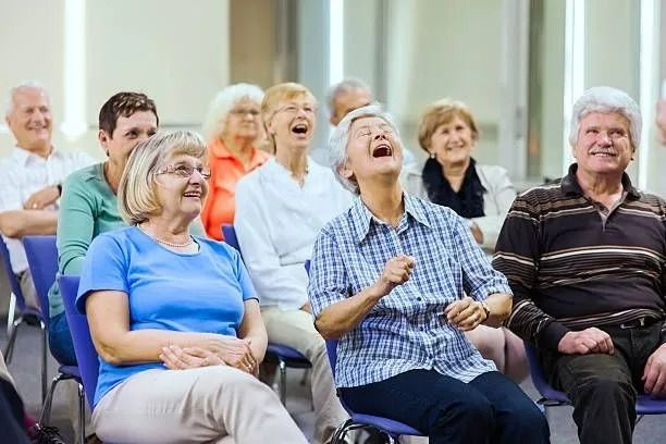 Smiling group seated indoors, laughing during a social gathering or class Smiling group seated indoors, laughing during a social gathering or class