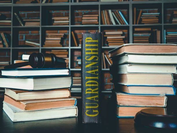 Stacks of books around a vertical GUARDIANSHIP book in a library-like setting. Stacks of books around a vertical GUARDIANSHIP book in a library-like setting.
