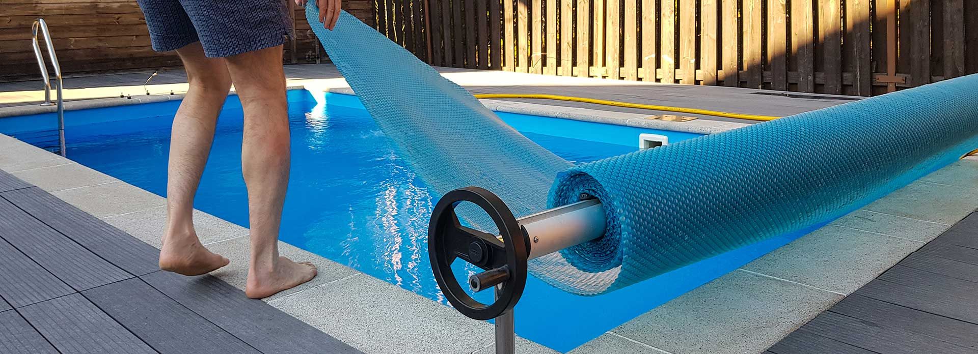 man covers swimming pool with cover for protection