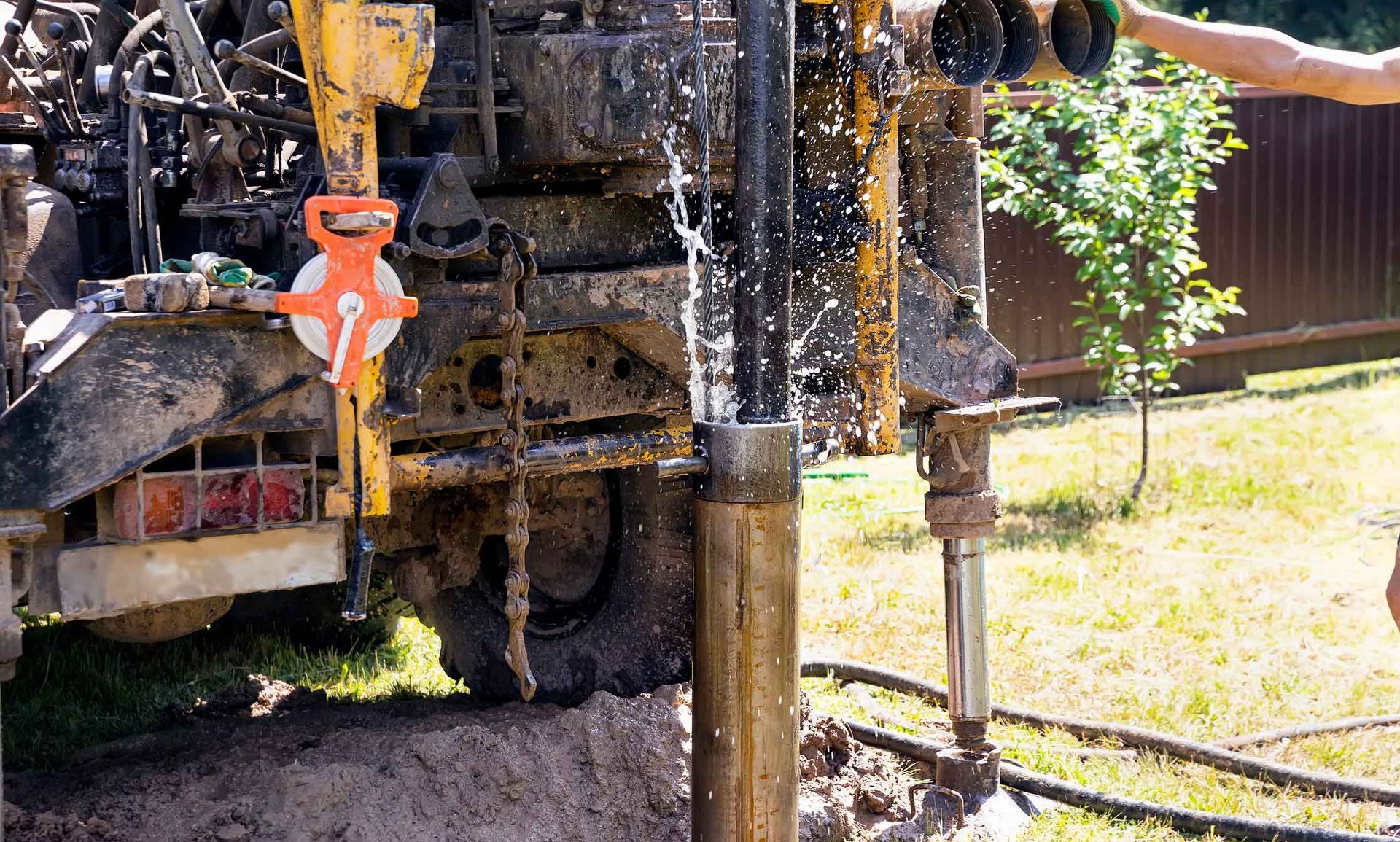 A man is drilling a hole in the ground next to a truck.