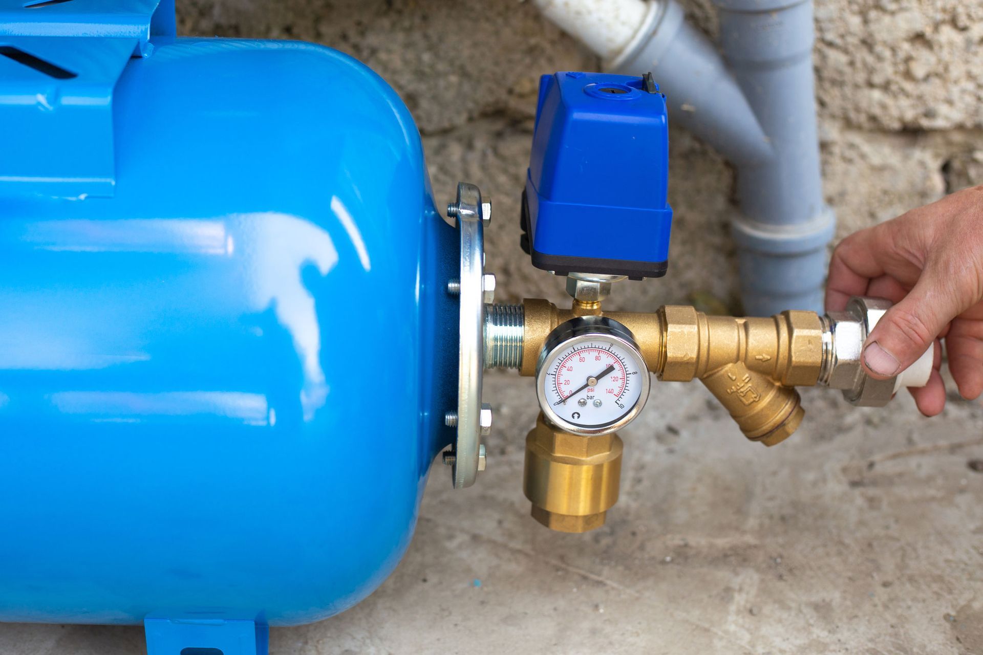 A person is fixing a water pump with a pressure gauge attached to it.